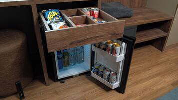 Una kitchenette compacta con un refrigerador empotrado y un mueble con aperitivos y bebidas.