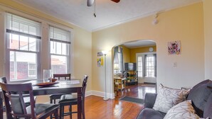 A dining area with a wooden table and chairs, a kitchen in the background, and a living room with a sofa and cushions. - Walk to Parks & Dining! Memphis Home w/ Yard (Memphis)
