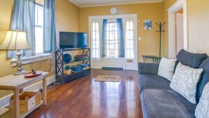 A living room with a sofa, a television, a lamp, and a wooden table. - Walk to Parks & Dining! Memphis Home w/ Yard (Memphis)