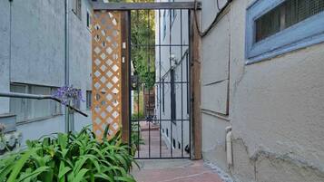 Un estrecho callejón con una entrada portonada, una reja de madera y un sendero que lleva a un edificio.