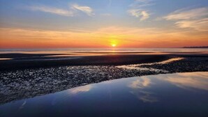 A sunset over a calm body of water with a rocky shoreline. - Great Hammcock Getaway, cozy home, hot tub, fire pit, beaches nearby. (Old Saybrook)