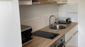 Una cocina moderna con horno empotrado, un lavamanos de acero inoxidable y un tostador compacto.