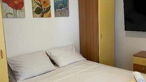 Una habitación de hotel con una cama, un televisor montado en la pared y tres cuadros.
