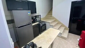 A compact kitchen with a refrigerator, stove, microwave, and a small countertop. - 819 · 2BR Townhouse | Garden | Sleeps 5 (Sheikh Zayed City)