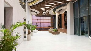 Um hall amplo com design moderno no teto, janelas grandes e plantas em vasos.