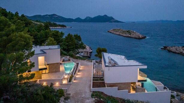 A modern villa with a pool, overlooking a coastal area with rocky outcrops and distant mountains. - Beachfront Villa Aurelia with heated Pool, Sauna & Fitness (Pijavičino (Pelješac))