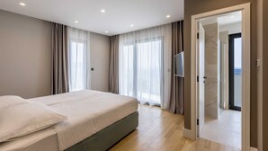 A modern hotel room with a large bed, a television, and a door leading to a balcony. - Beachfront Villa Aurelia with heated Pool, Sauna & Fitness (Pijavičino (Pelješac))