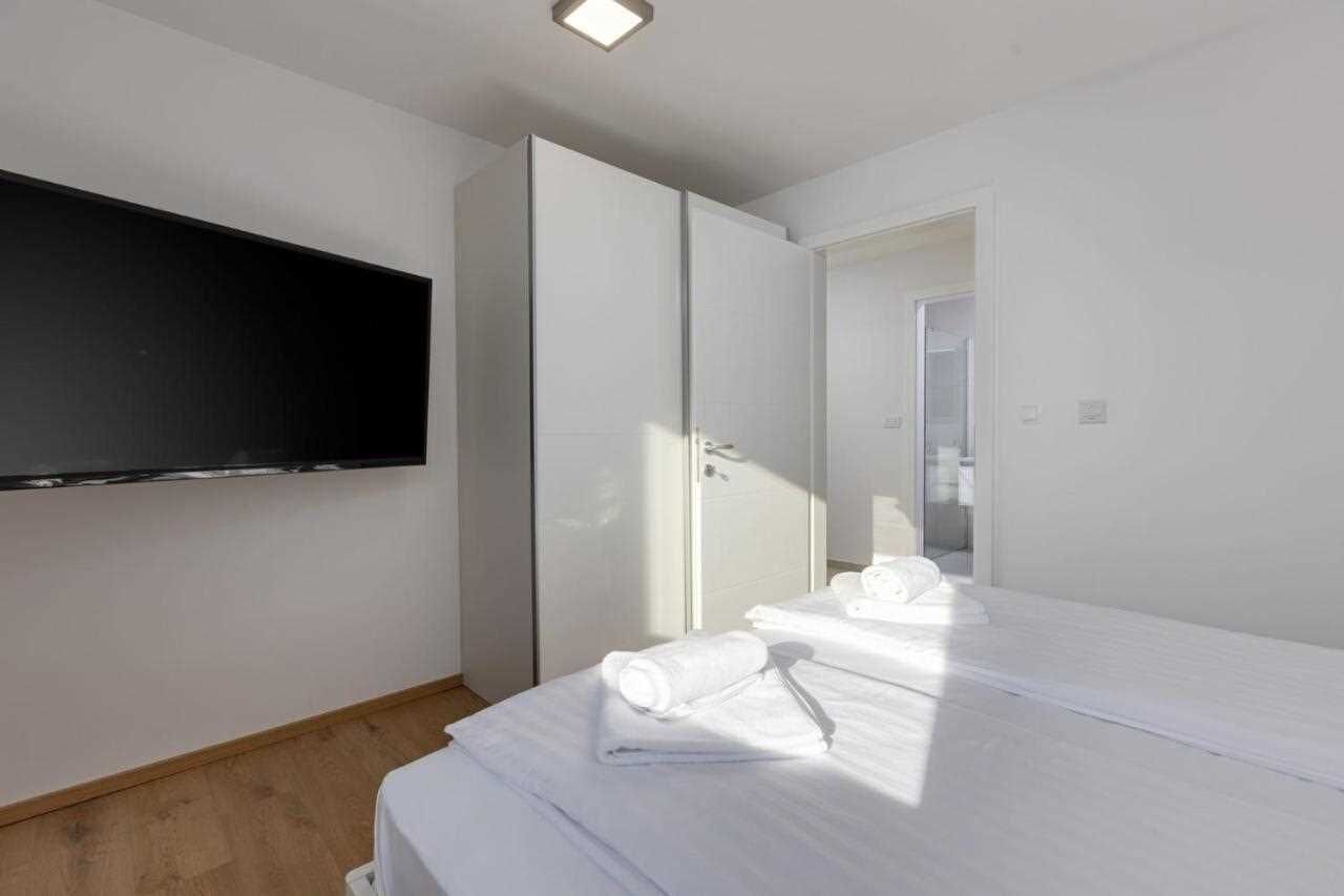 Una habitación de hotel con cama, televisor montado en la pared y armario.