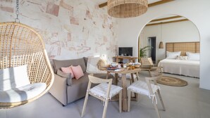 Una habitación moderna con una silla colgante, un sofá, una mesa de comedor con sillas y una cama con cabecera de madera.