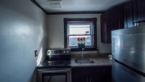 A compact kitchen with a stove, oven, sink, and a refrigerator.