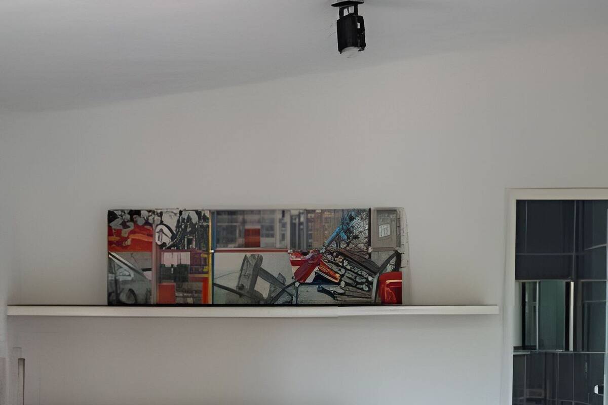A bedroom with a bed, a nightstand, a wall-mounted shelf with artwork, and a door leading to a bathroom.