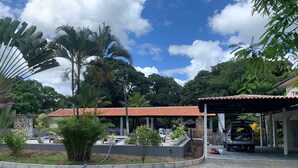 A covered outdoor area with a stone wall, a small pool, and a car parked under a roofed pavilion.