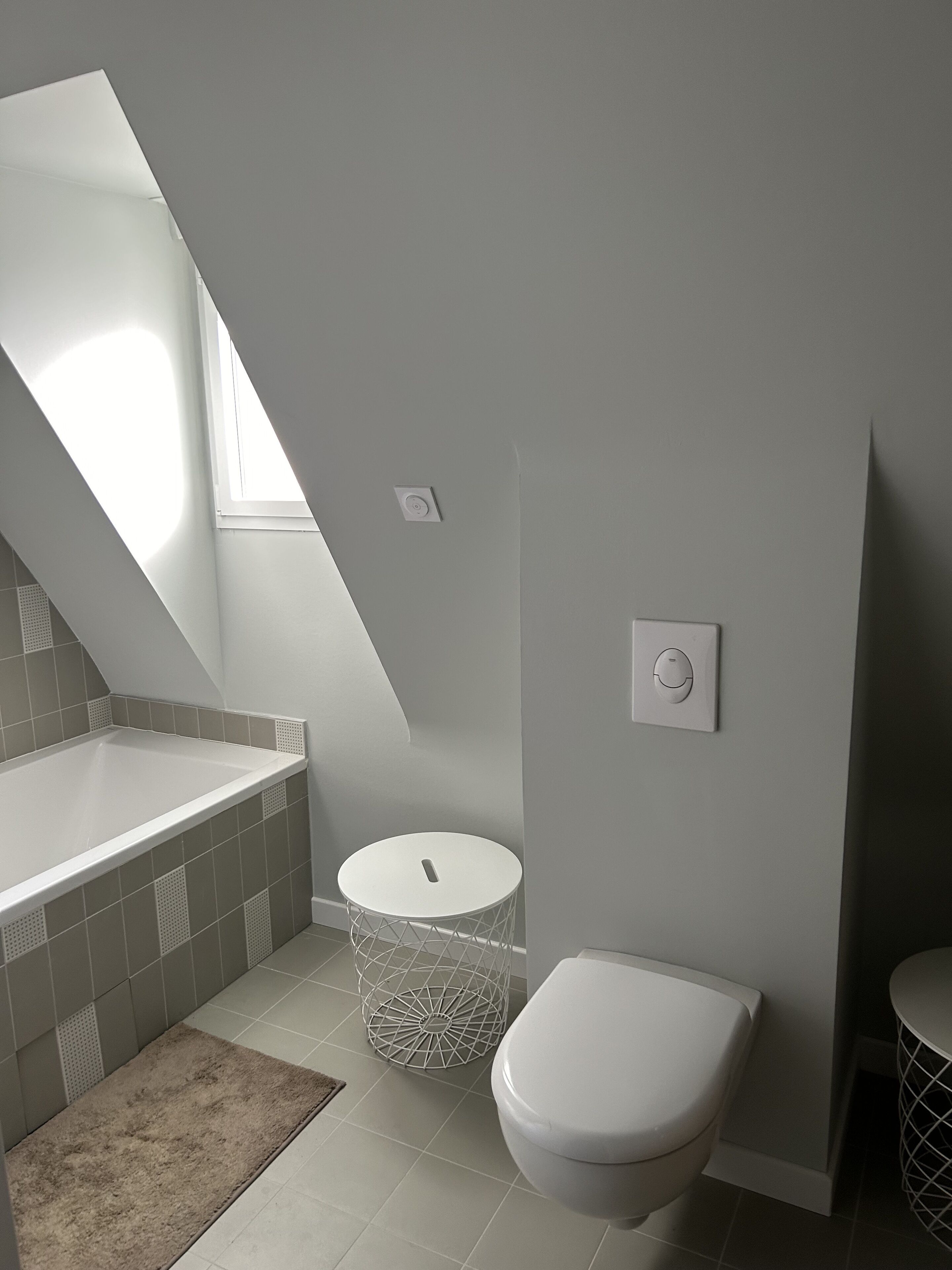 A modern bathroom with a bathtub, toilet, and a small round table.