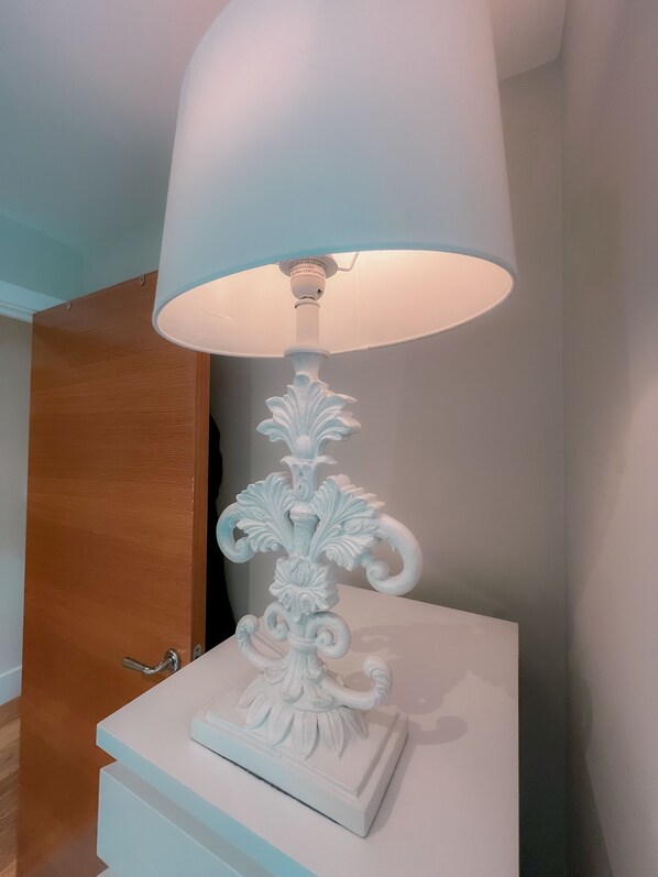 Une lampe de table blanche, dotée d’un pied décoratif et d ’un grand abat-jour blanc.