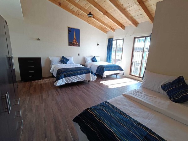 A bedroom with two beds, a sofa, a wardrobe, and a picture of the Eiffel Tower on the wall. - Capital O Casa Rotter (San Cristóbal de las Casas)