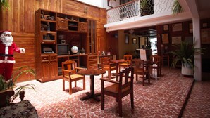 Un vestíbulo de hotel con muebles de madera, un árbol de Navidad y un balcón con plantas.