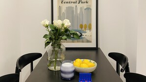 Taula de menjador amb un quadre emmarcat de Central Park de Nova York, un ram de flors blanques, un got de llet i un bol de limones.