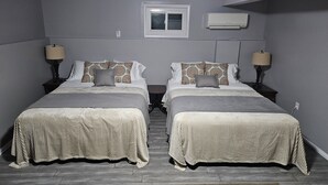 Habitación doble con dos camas, ventana, aire acondicionado y una alfombra.