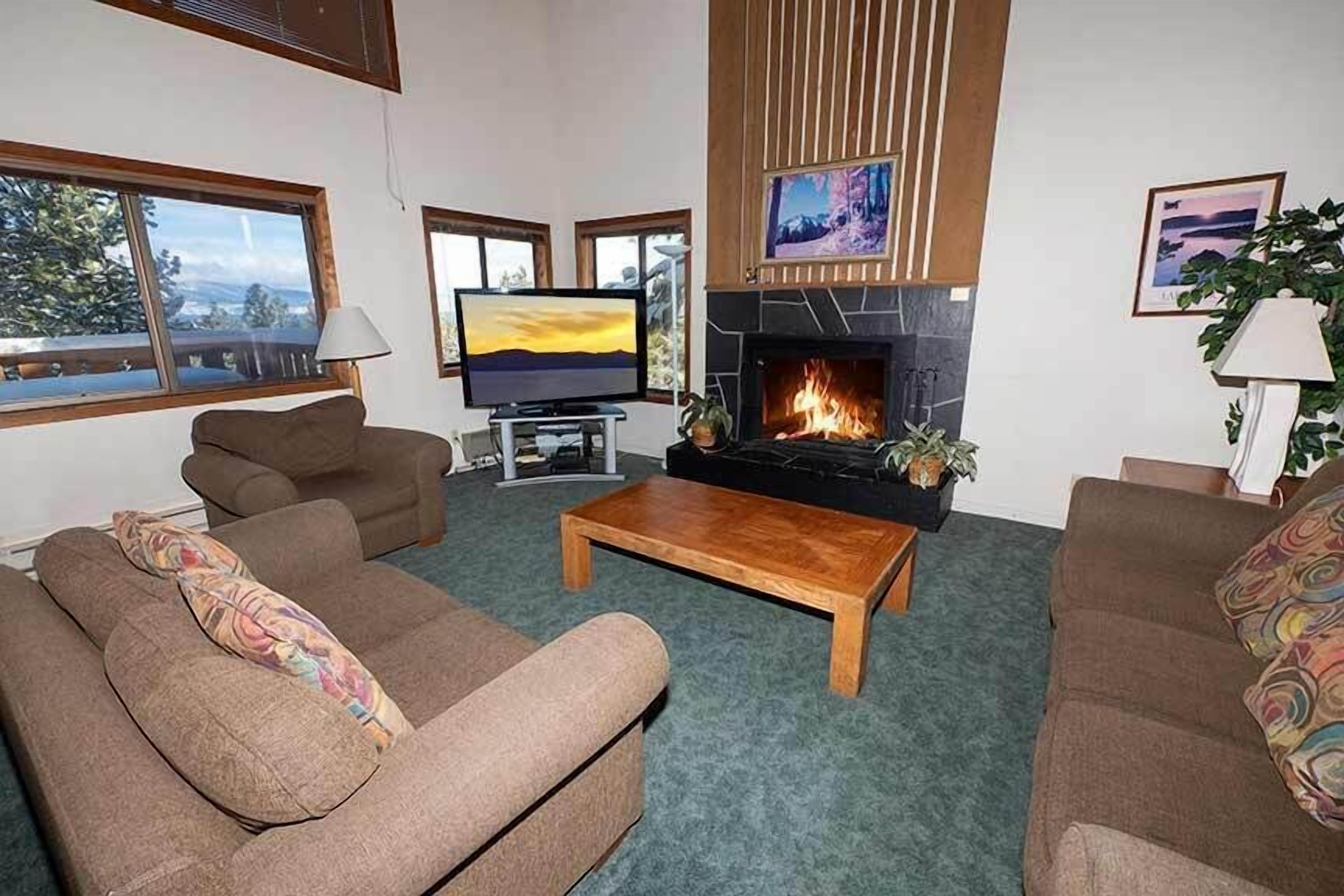 A living room with a fireplace, two sofas, a coffee table, and a TV.
