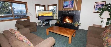 A living room with a fireplace, two sofas, a coffee table, and a TV.