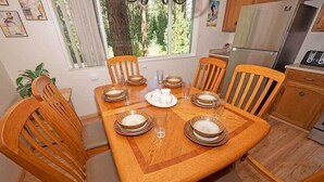 Un coin repas avec une table en bois, dressée pour six personnes, entourée de chaises en bois dotées d’assises rembourrées.