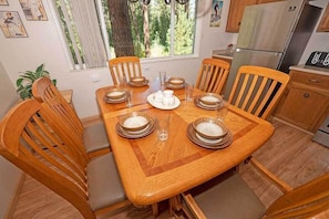 Comedor con una mesa de madera dispuesta para seis personas, rodeado de sillas de madera con asientos acolchados.