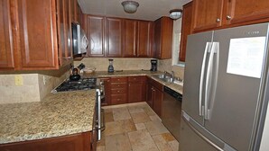 A kitchen with wooden cabinets, granite countertops, a stainless steel refrigerator, and a gas stove. - Waterfront Home, Private Hot Tub/Boat Dock - Views! (South Lake Tahoe)