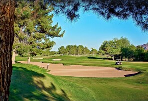 Ein Golfplatz mit Sandbunkern, Putting-Grün und blauem Himmel.