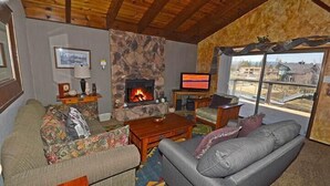 A cozy living room with a fireplace, a television, and a sofa. - Waterfront Home with Mountain Inspired Decor, Private Hot Tub and Boat Dock 2085S~ (South Lake Tahoe)