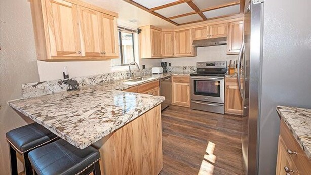 A kitchen with wooden cabinets, a marble countertop, and stainless steel appliances. - Waterfront Home with Mountain Inspired Decor, Private Hot Tub and Boat Dock 2085S~ (South Lake Tahoe)