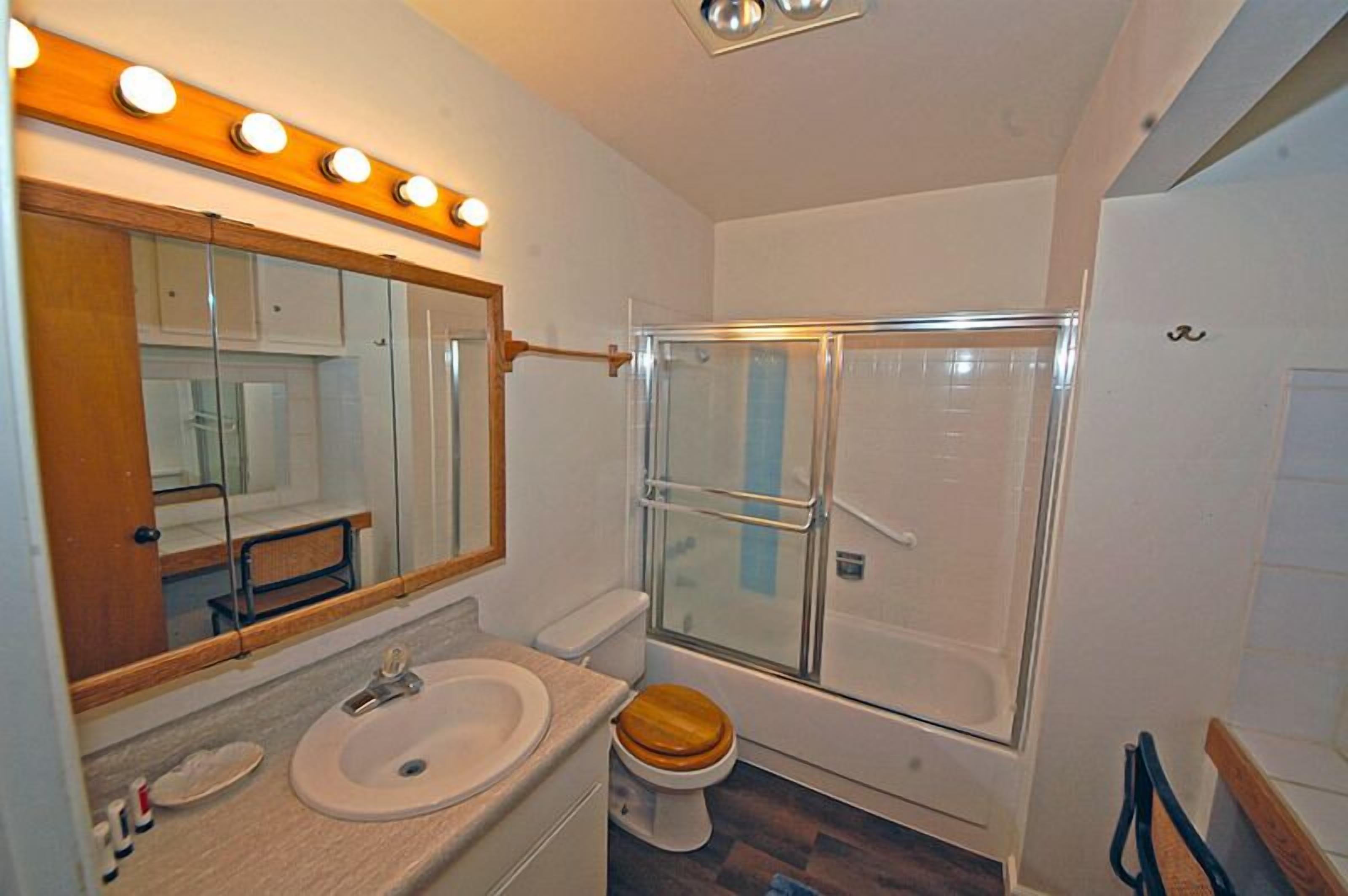 A bathroom with a sink, mirror, and shower.