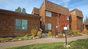 Un bâtiment moderne à deux étages, doté d’une façade en bois et d’un jardin paysager à l’avant.