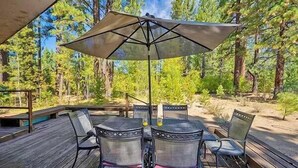 An outdoor deck with a table and chairs, surrounded by trees.