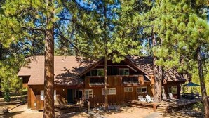 A wooden cabin with a two-story structure, a deck, and a covered outdoor seating area.