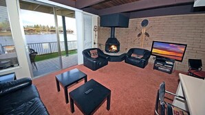 A cozy living room with a fireplace, comfortable seating, a television, and a view of a lake. - Waterfront Condo - Easy Lake Access, Private Boat Dock (South Lake Tahoe)