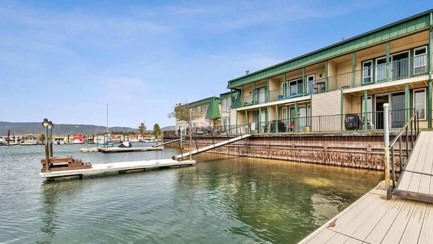 A waterfront hotel with a dock, a covered walkway, and a view of boats and hills in the background. - Waterfront Condo - Easy Lake Access, Private Boat Dock (South Lake Tahoe)