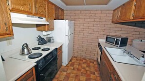 A compact kitchen with wooden cabinets, a white stove, a refrigerator, and a microwave. - Waterfront Condo - Easy Lake Access, Private Boat Dock (South Lake Tahoe)