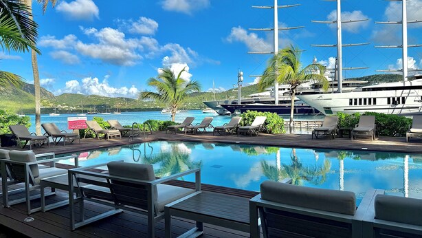 A pool area with lounge chairs, a wooden deck, and a view of boats and hills. - Stunning Waterfront Suite, Antigua English Harbour (English Harbour)