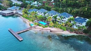 An aerial view of a coastal resort with multiple villas, a swimming pool, and a dock extending into the water. - Stunning Waterfront Suite, Antigua English Harbour (English Harbour)