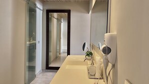A modern bathroom with a large mirror, a hairdryer, and a sink. - Stunning Waterfront Suite, Antigua English Harbour (English Harbour)