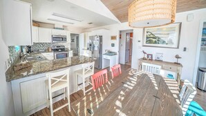 A spacious kitchen with white cabinetry, a granite countertop, and a hanging rattan light fixture.