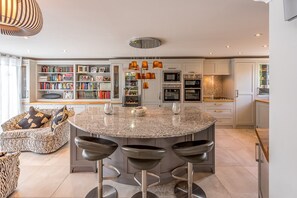 Une cuisine moderne dotée d’un îlot central, de tabourets de bar, d’étagères intégrées et d’un coin repas avec un canapé à motifs zébrés.