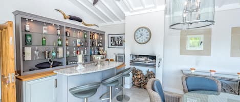 Una cocina moderna con barra, taburetes de bar, ventilador de techo, reloj y chimenea.