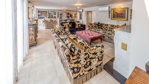 A spacious living room with a large sofa set, a coffee table, and a dining area with a marble countertop.