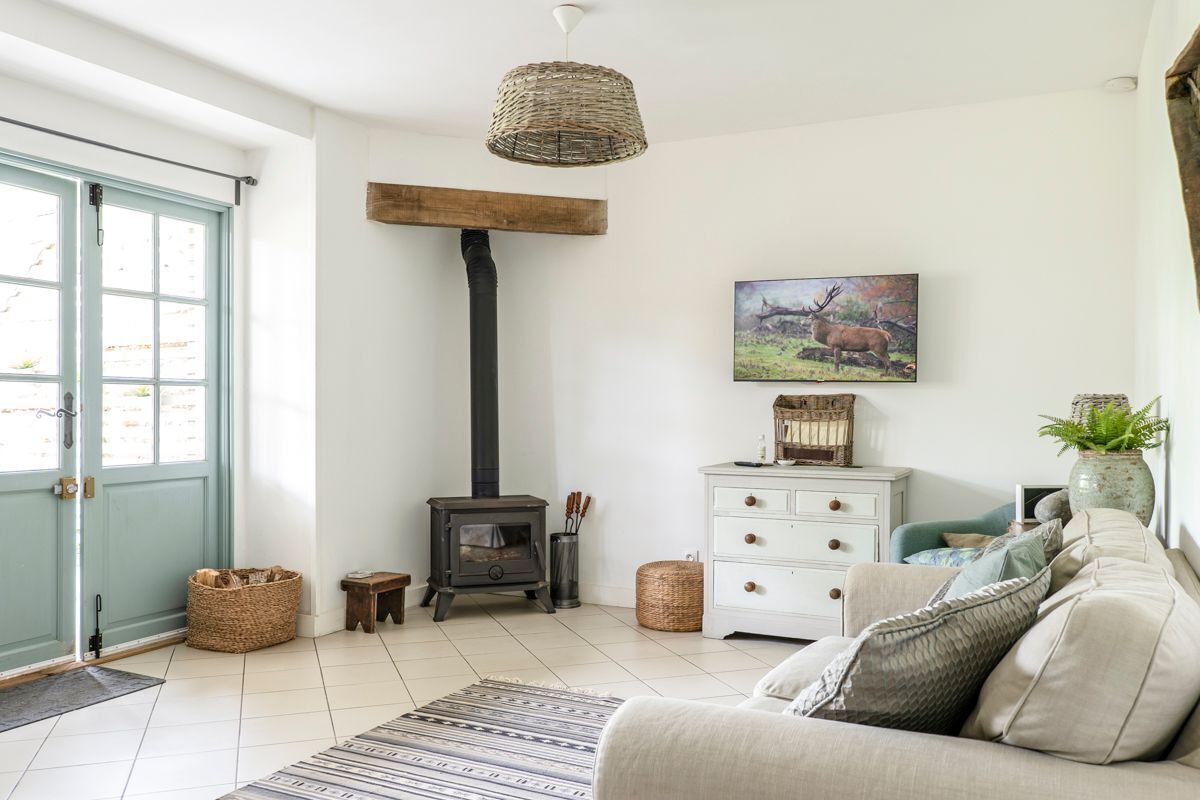 Una sala de estar acogedora con chimenea, un sofá, un aparador blanco y un cuadro de un ciervo.