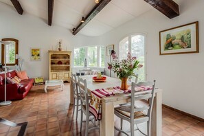 Un comedor con una mesa y sillas de madera, un sofá rojo y una estantería.
