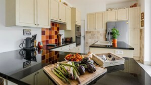 Una cocina moderna con armarios de colores claros, encimera negra y una variedad de verduras frescas sobre la encimera.