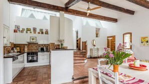 A spacious kitchen with white cabinets, a central island, and a dining area with a table set for two. - Mas Mayeaux - Six Bedroom Villa, Sleeps 12 (Vaison-la-Romaine)