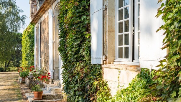 Un bâtiment historique aux murs recouverts de lierre, avec un chemin de pierre menant à l’entrée.