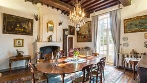 Une salle à manger avec une table en bois, des chaises, un lustre et divers éléments de décoration murale.